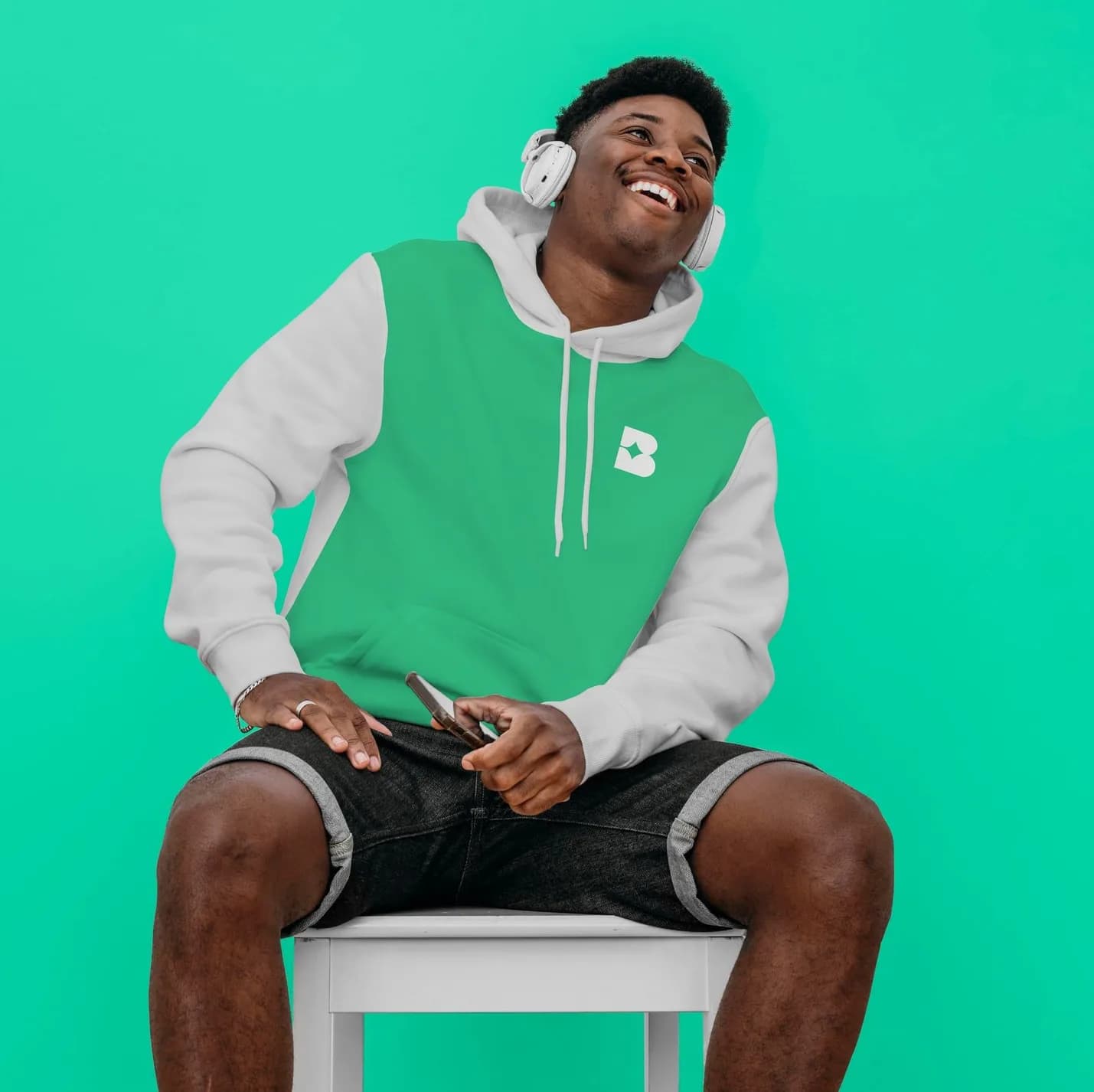 A man laughing in the Bublr hoodie, green and white, headphones on