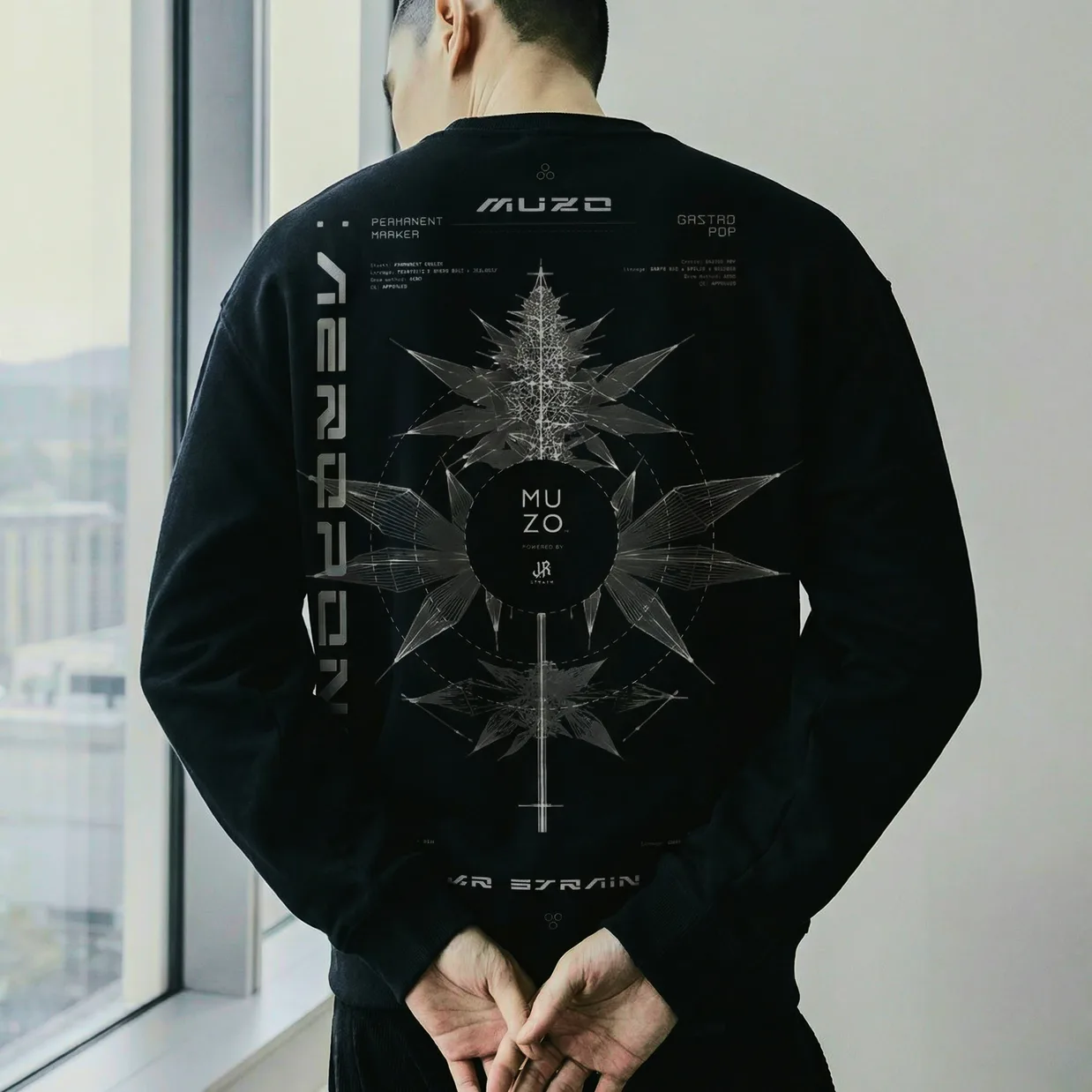The Aeroponics back print worn: a plant diagram drawn in fine white line around the MUZO and JR roundel, with the strain data set above and below it