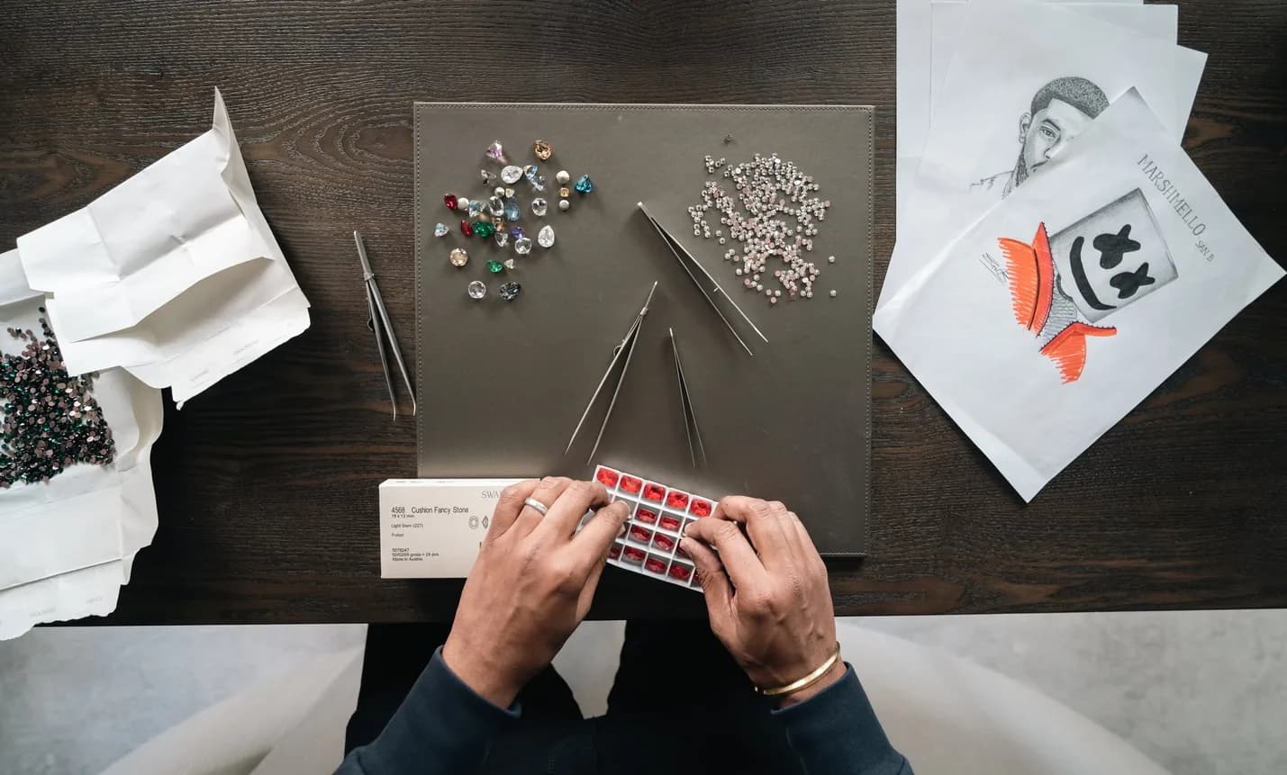 The desk from above: the sketch, the loose crystals, the tweezers, a Swarovski box