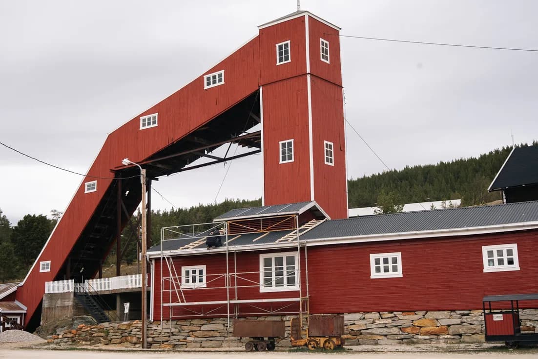 The red headframe and hoist house of a historic mine, still standing over the shaft.
