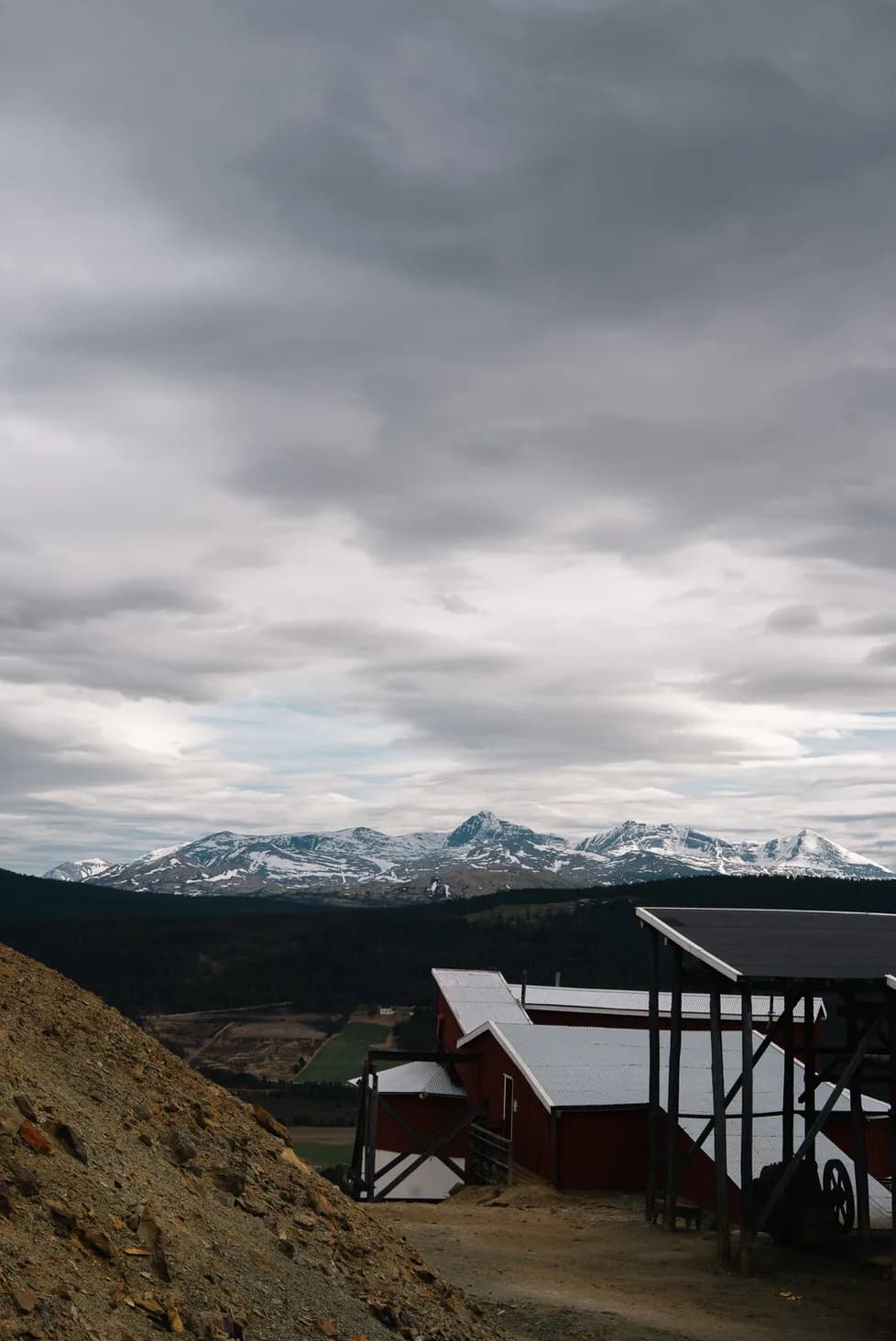 A red mine building on the slope, the cableway running out above it, snow on the ridge beyond.