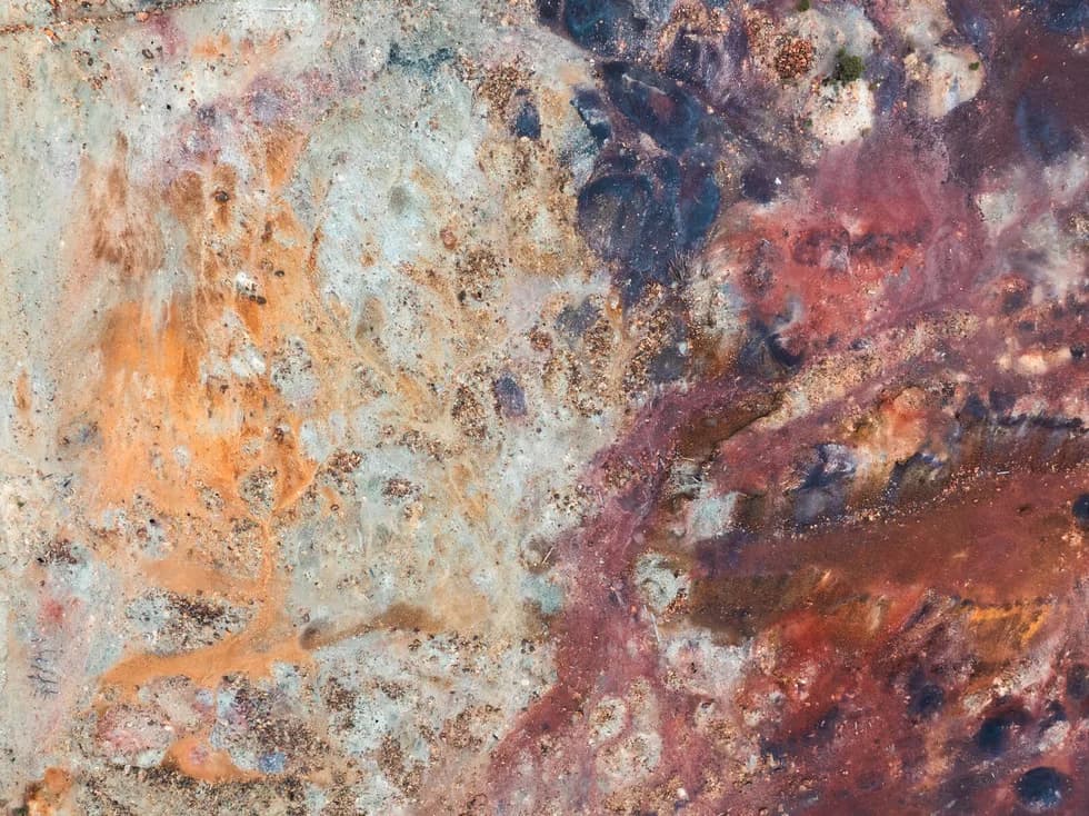 Tailings from directly above, the ground turned rust, white and copper by what is in it.
