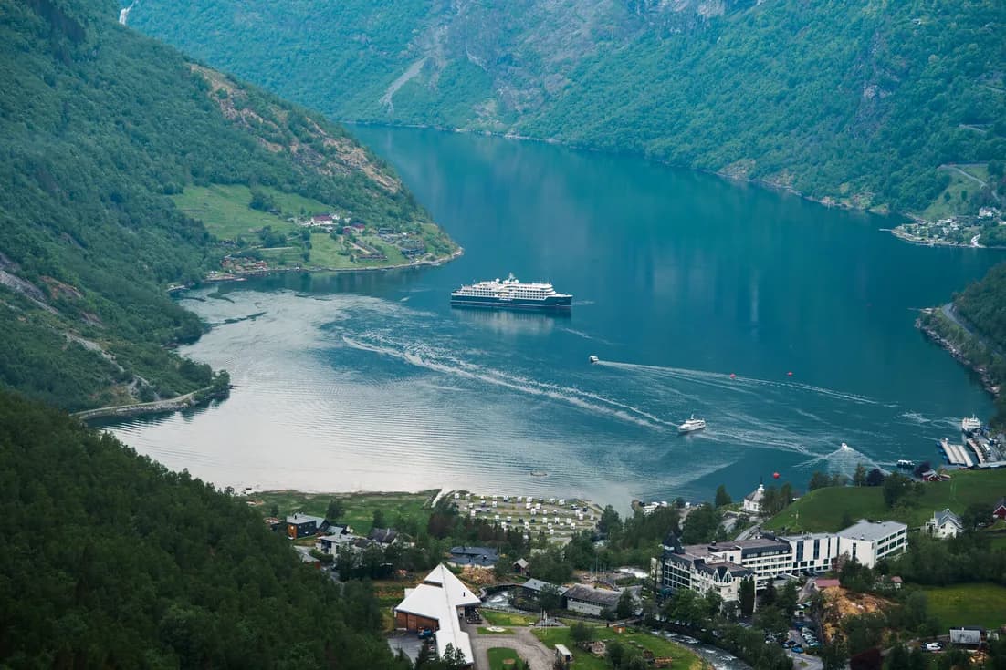 Geiranger from above, a cruise ship at anchor and the village along the head of the fjord.