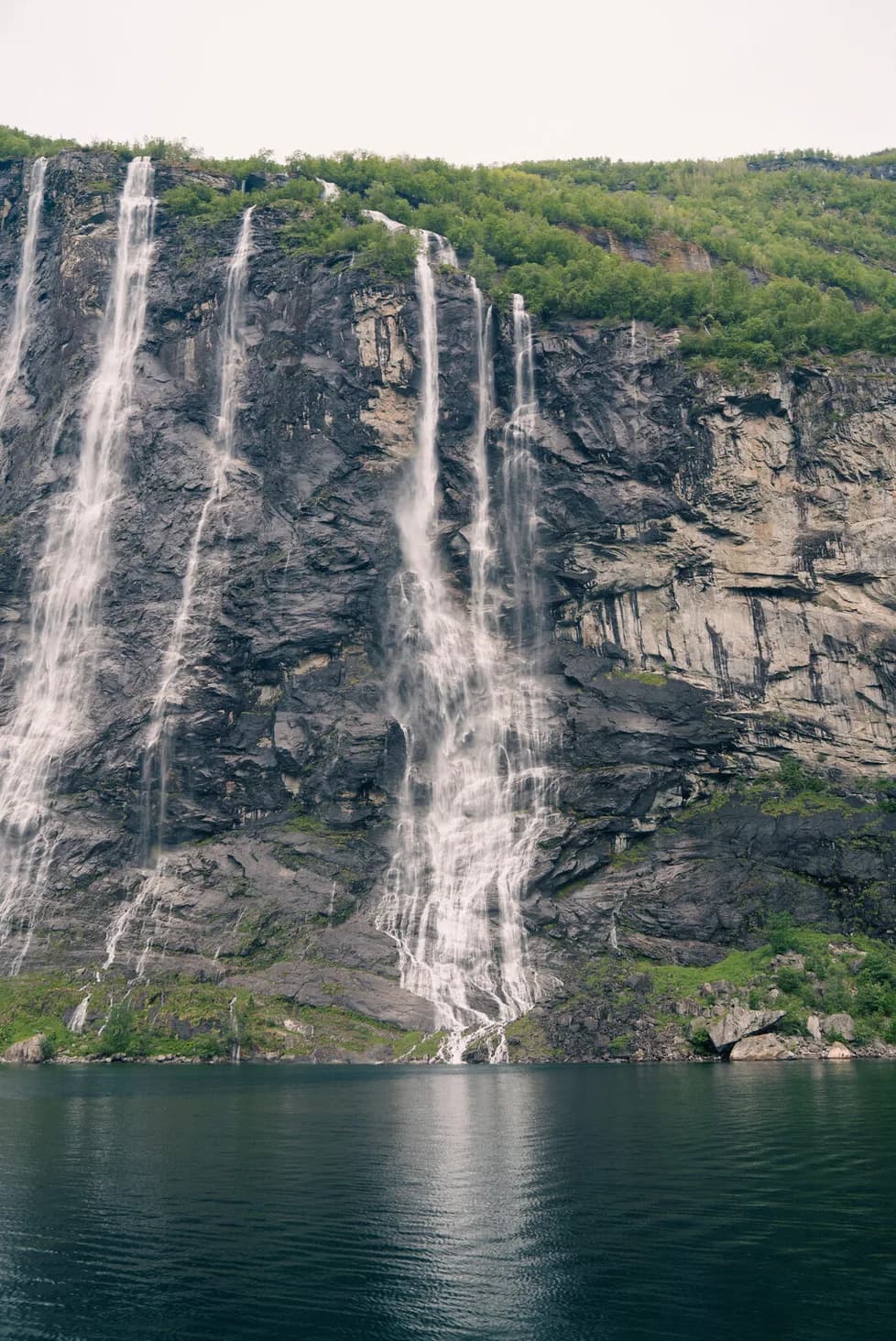 The Seven Sisters close, the falls braiding down the rock face into the fjord.