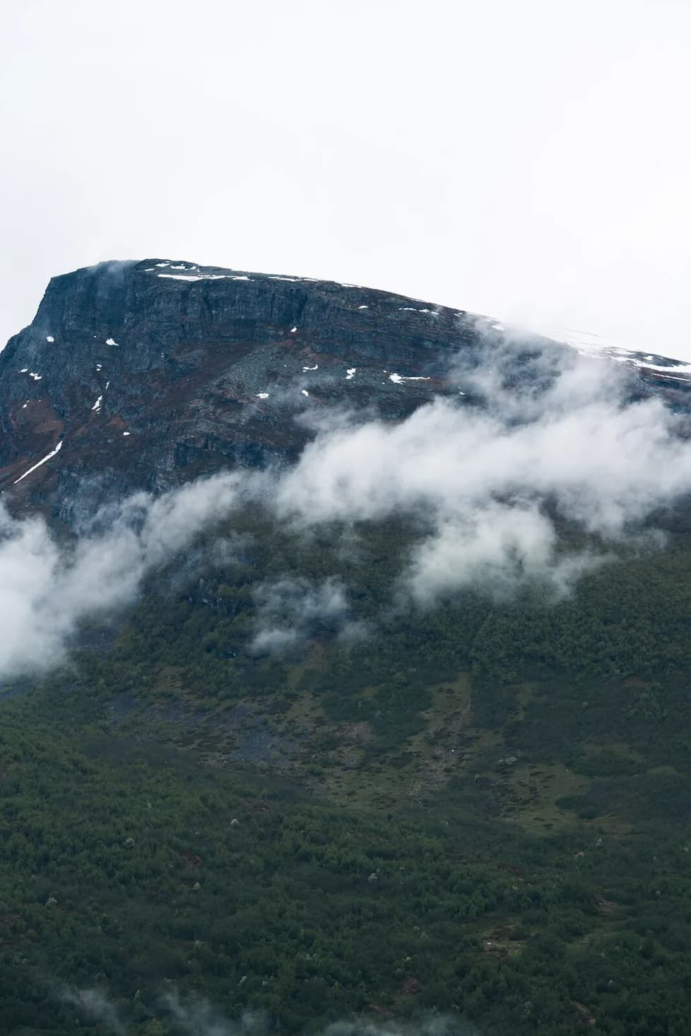 The cliff face half in cloud, snow in its gullies