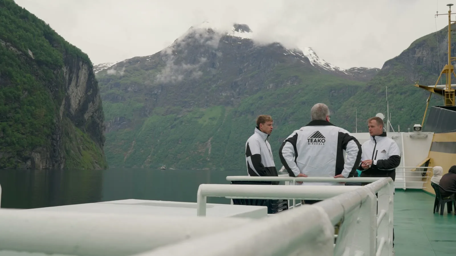 Three of the team in Teako jackets on a ferry deck in the Geiranger fjord