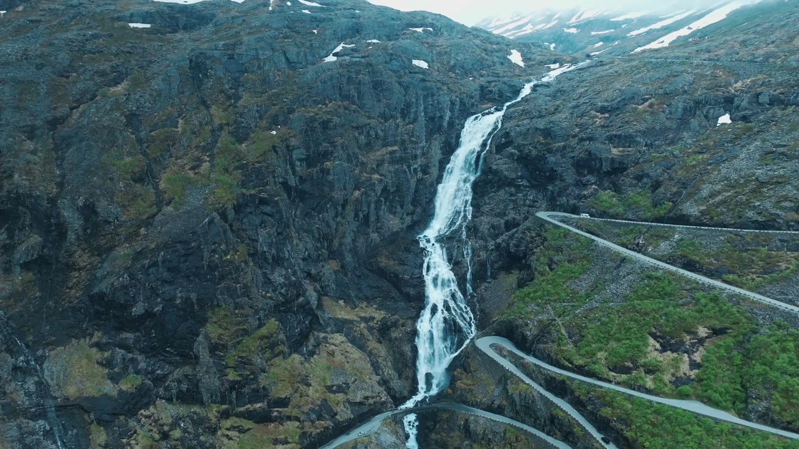 A waterfall and the hairpin road beside it, from the air